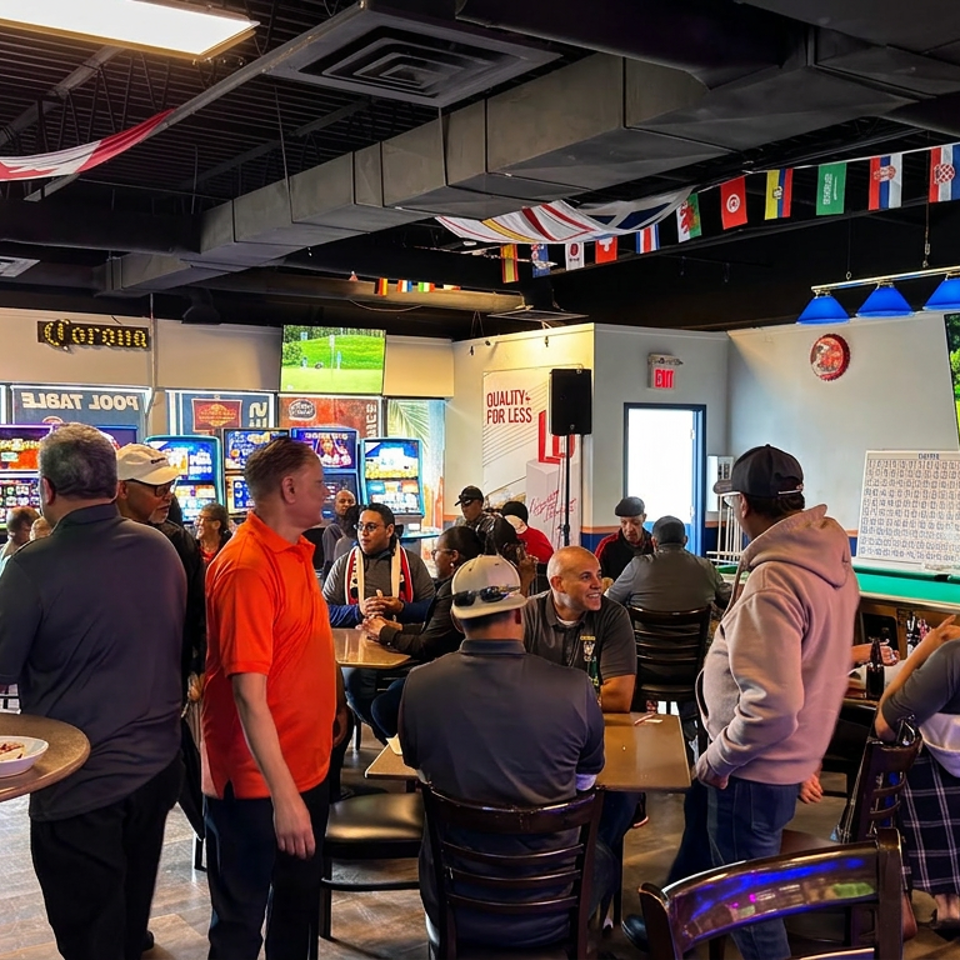 Busy sports bar filled with patrons, televisions showing soccer, international flags overhead, and tables with food and drinks.