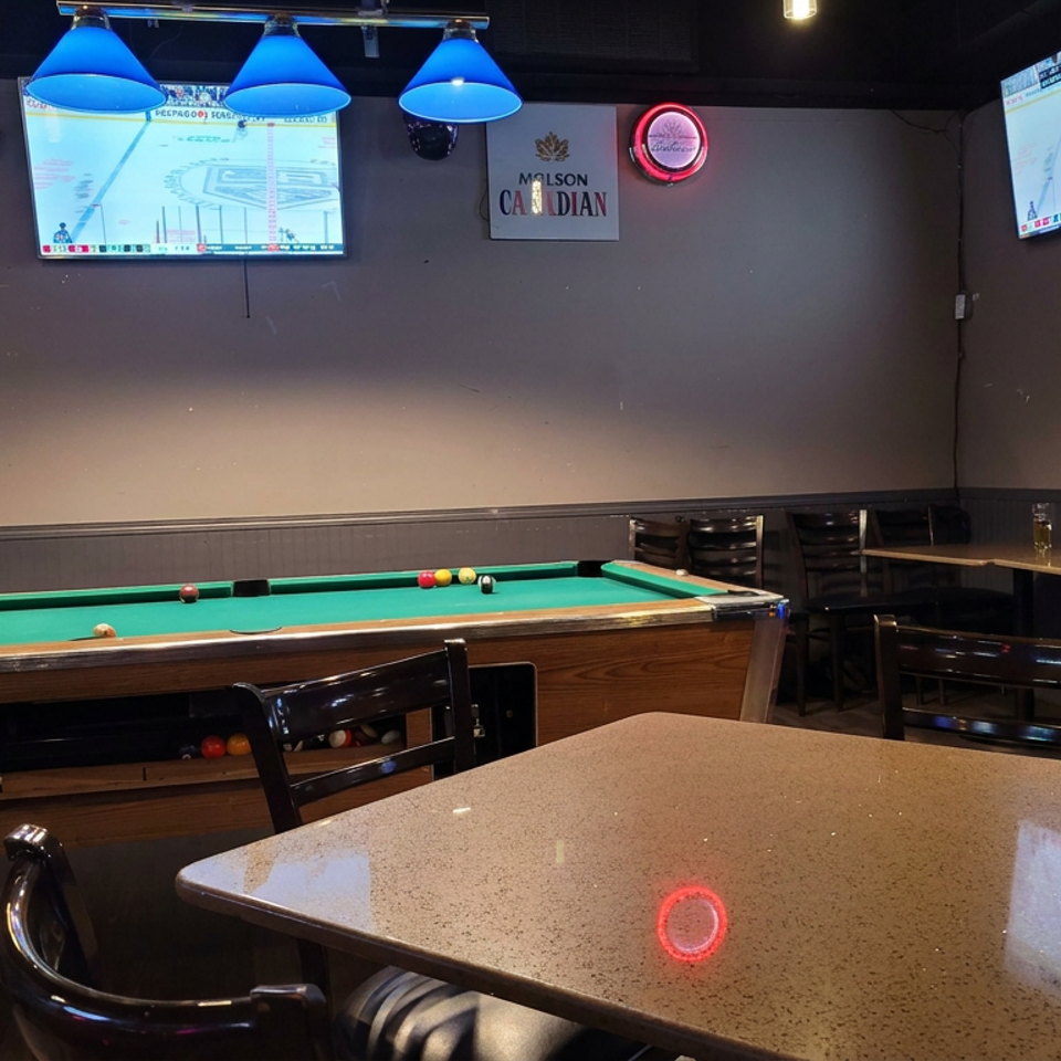 Restaurant game room featuring a pool table, high-top tables, sports televisions, blue pendant lights, and a Canadian-themed wall sign.